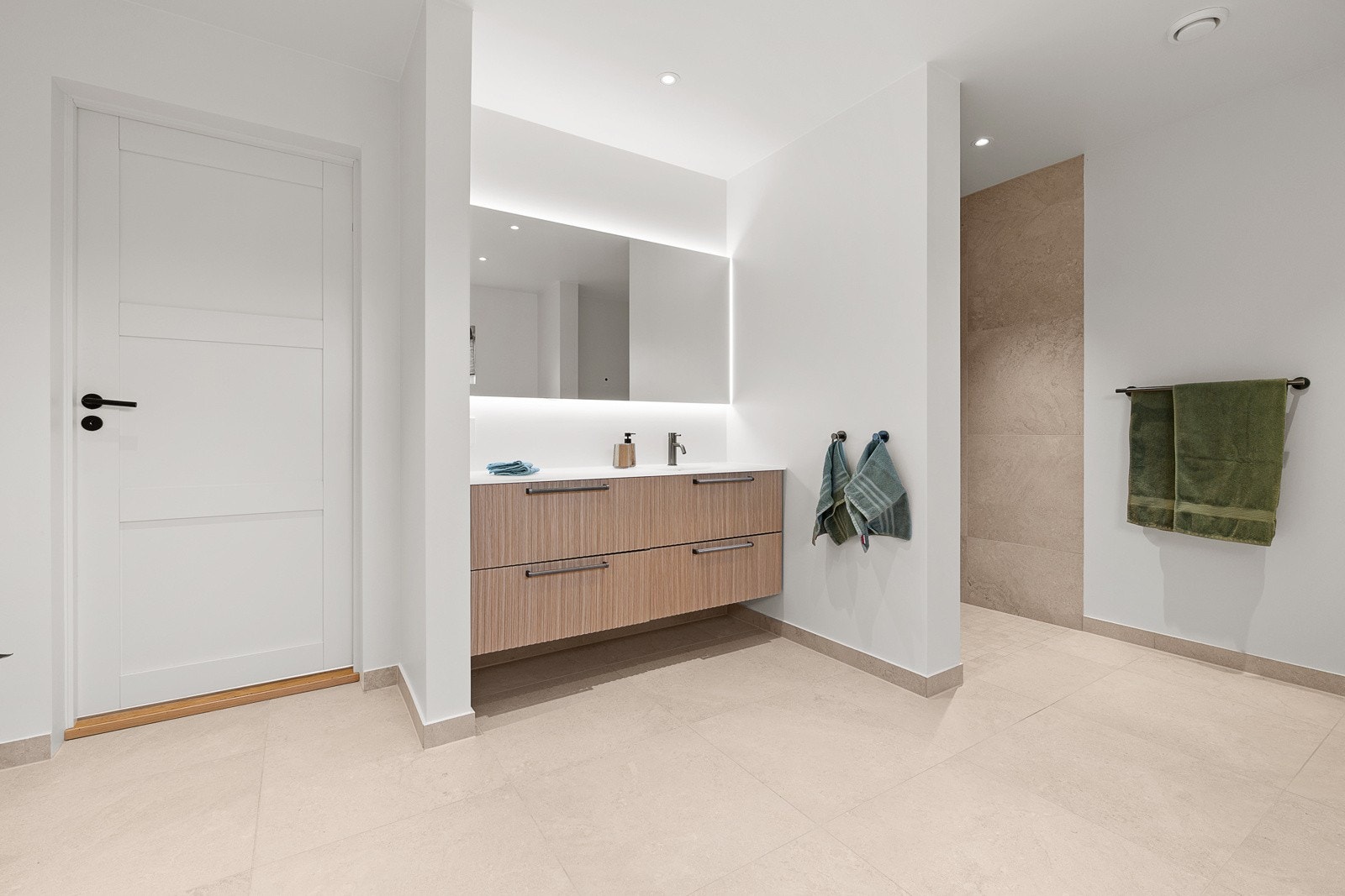 Moderne og flott bad fra 2024. Badet er utstyrt med heldekkende servant i baderomsinnredning, stort speil med lys, dusjsone, vegghengt toalett og opplegg for vaskemaskin Galleribilde