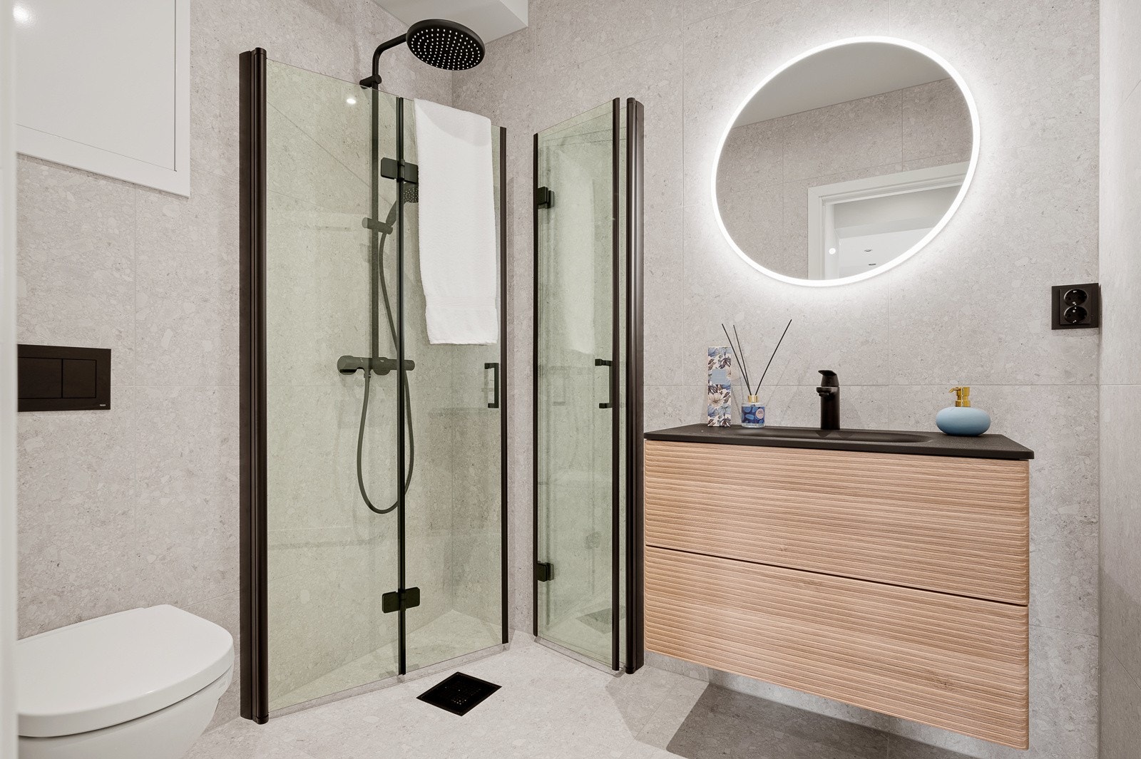 Delikat flislagt bad med dusjhjørne, toalett og servant Galleribilde