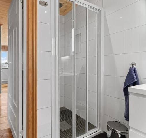 Hoved bad 1. etasje med med vegg-hengt toalett, flisbelagt dusj-nisje med waterfall dusj Galleribilde