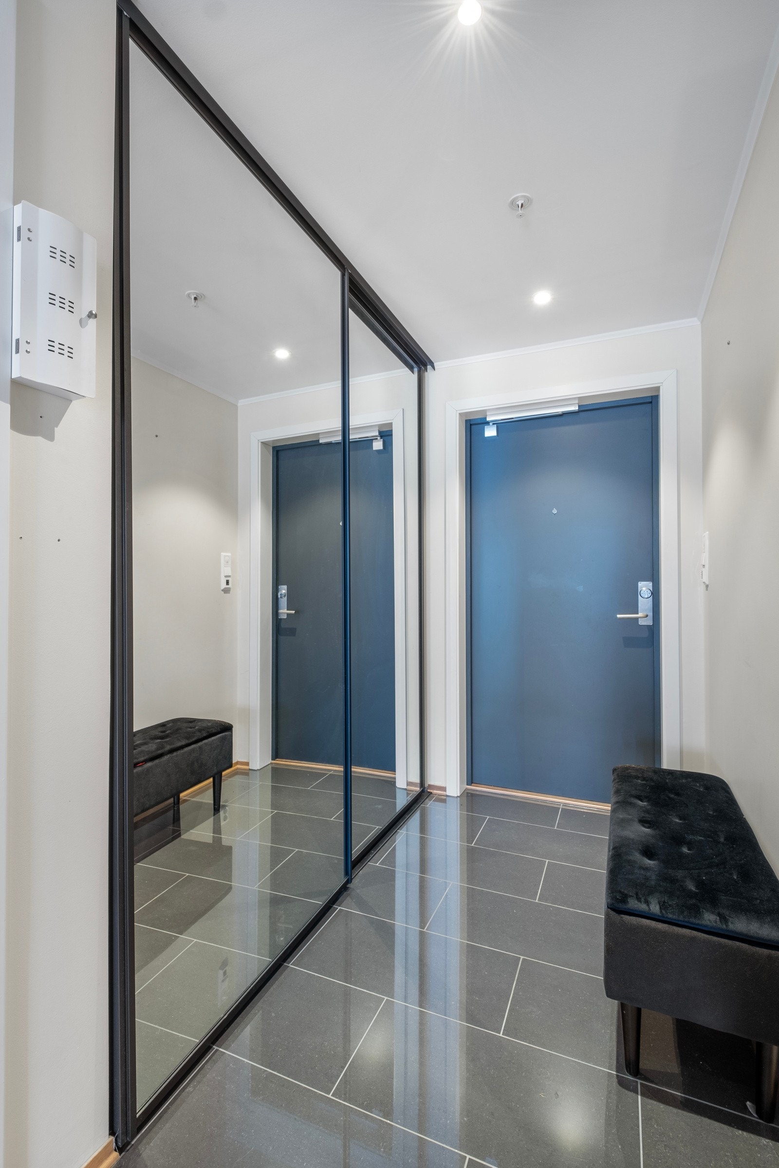 Flislagt gang med stor skyvedørsgarderobe med speilfronter Galleribilde