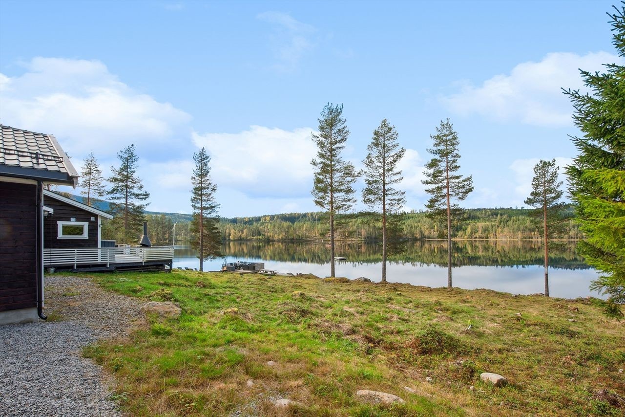 Eiendommen ligger i et skrånende terreng ned mot vannet, omkranset av skog. Galleribilde