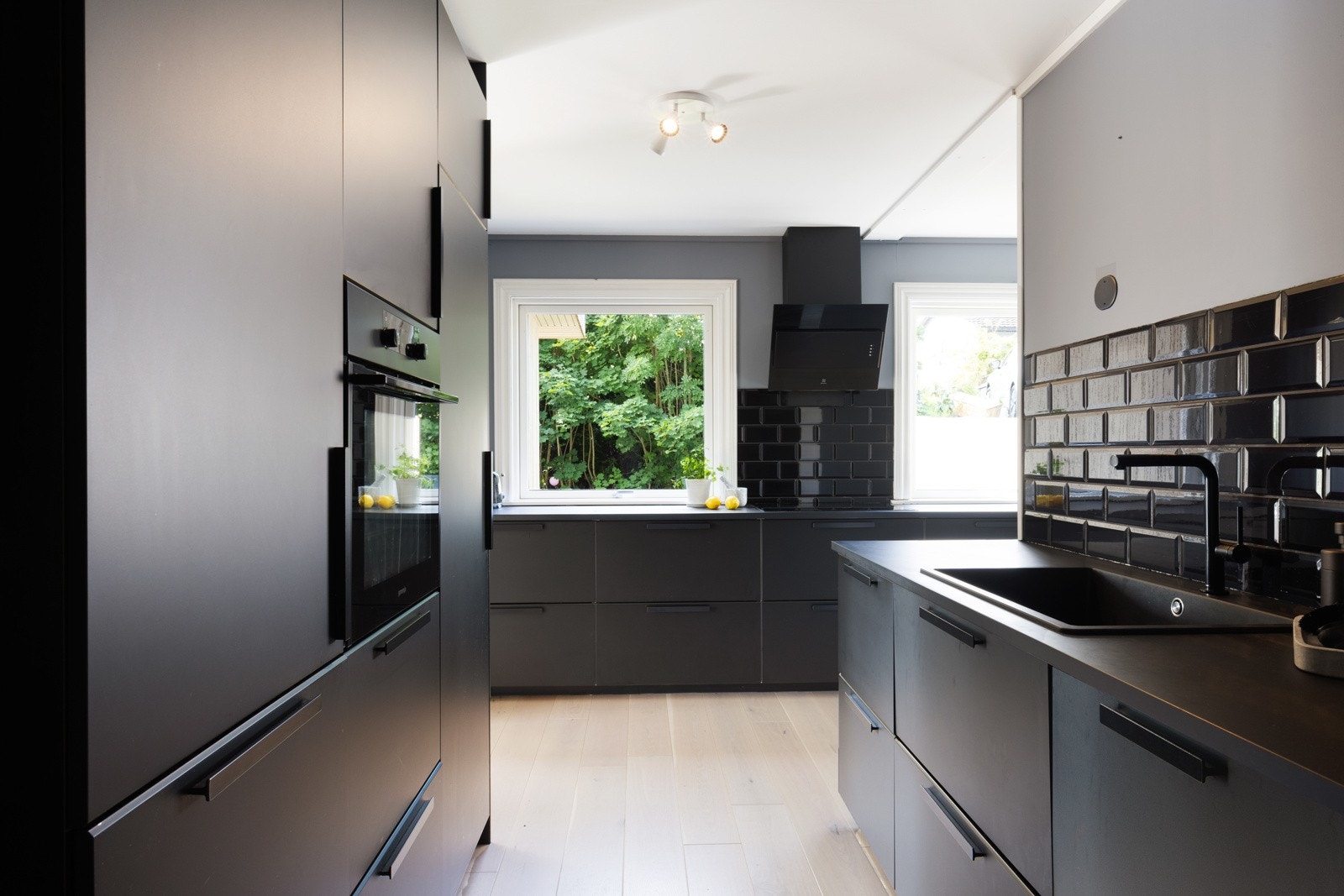 Stilren og tidløs innredning med mørke slette fronter og laminert benkeplate med nedfelt oppvaskkum med ett-greps armatur. Galleribilde