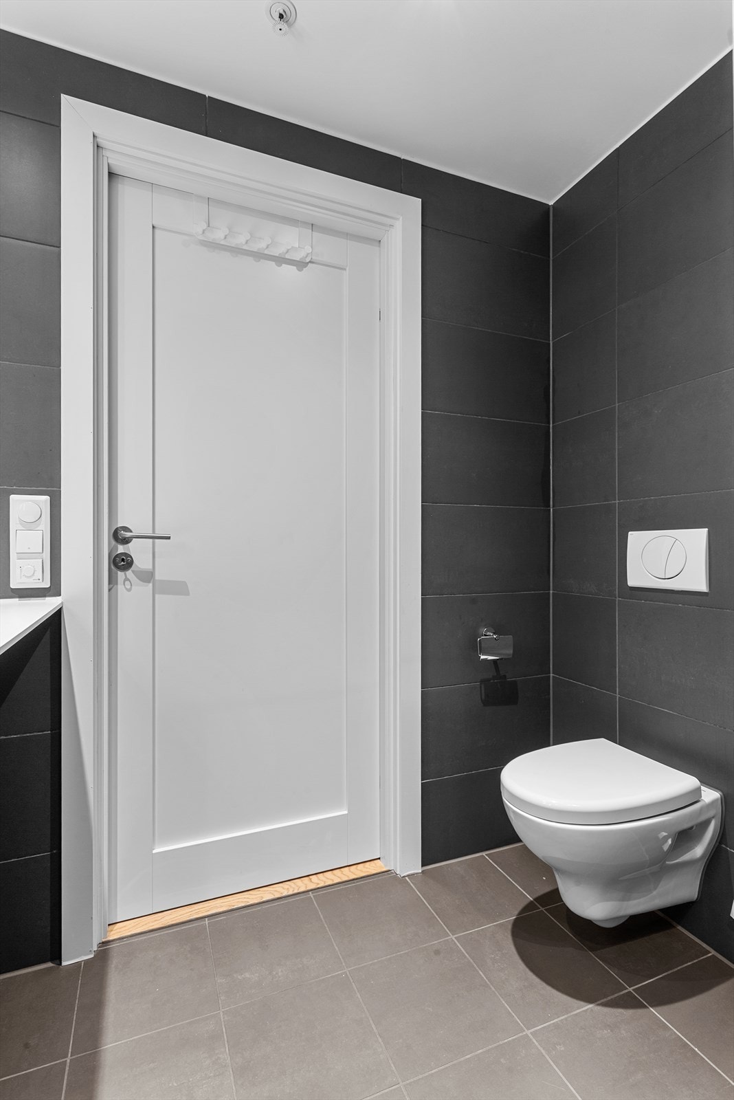 Heldekkende servant med underskap, speil og belysning, vegghengt toalett og dusj med glassvegger i herdet glass. Opplegg for vaskemaskin. Galleribilde