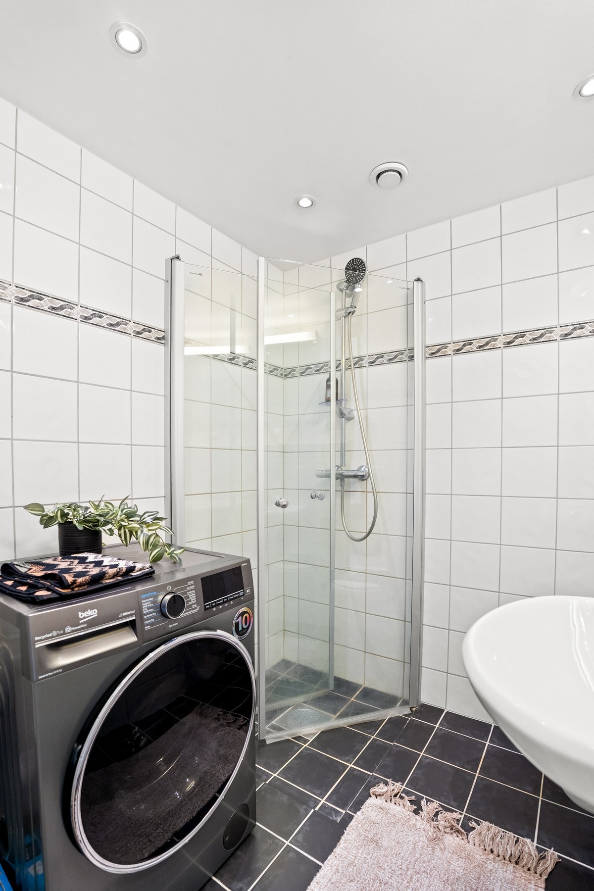 Stilrent baderom med gulvvarme, opplegg for vaskemaskin og moderne downlights. Galleribilde