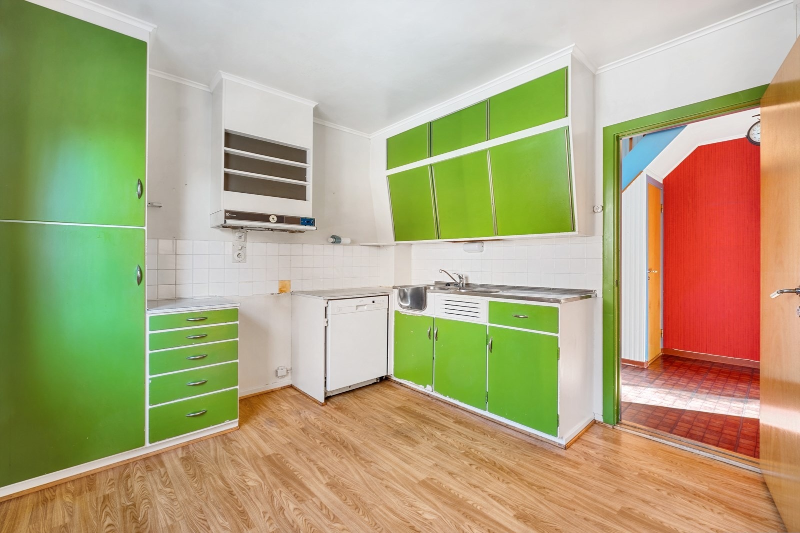 Kjøkkenet har en eldre innredning med slette malte fronter og benkeplate i laminat Galleribilde