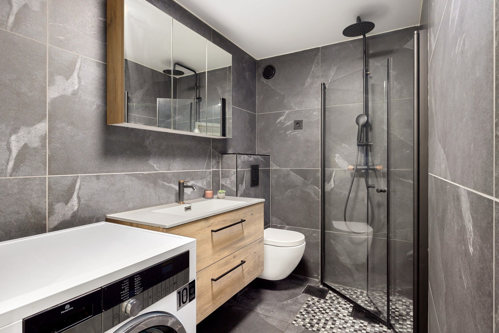 Lekkert bad fra 2023 gjennomført i en moderne stil med mørke fliser og sorte detaljer. Galleribilde