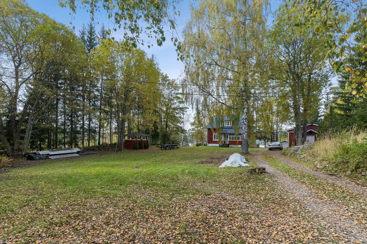 Eiendommen har en stor og flat gressplen, omkranset av trær. Galleribilde