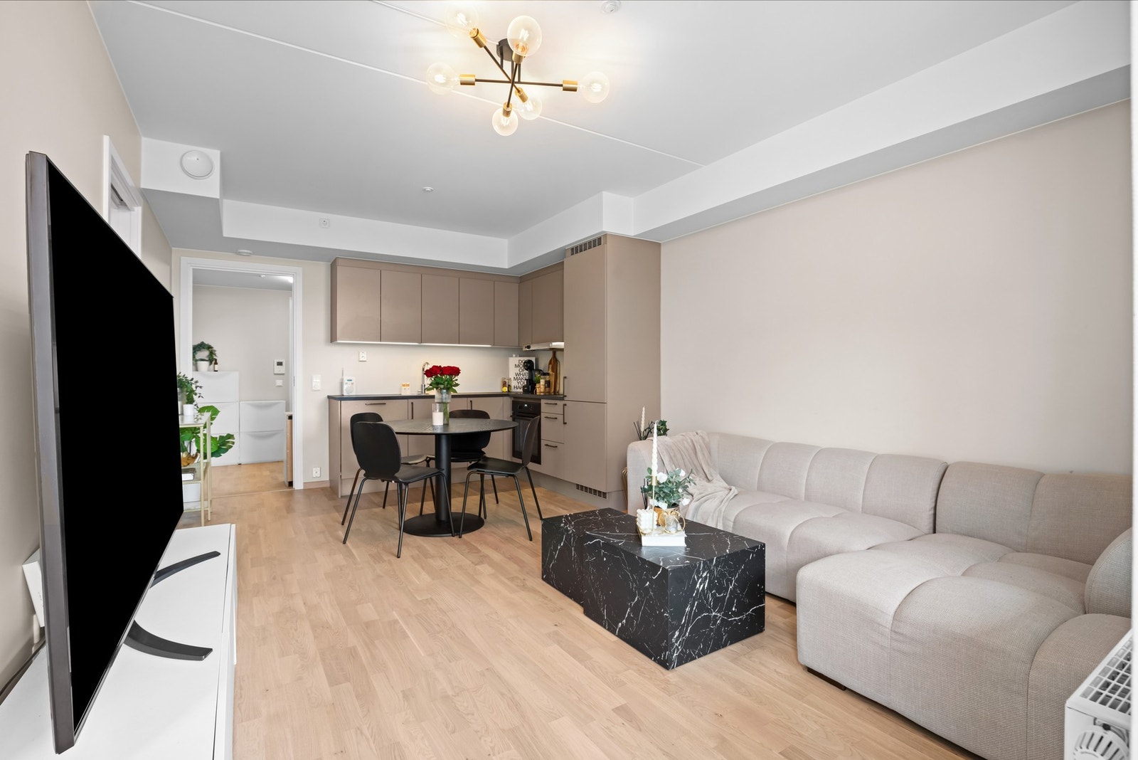 Stilfullt kjøkken med beige skapfronter og sorte håndtak som står i stil med stekeovnen. Galleribilde