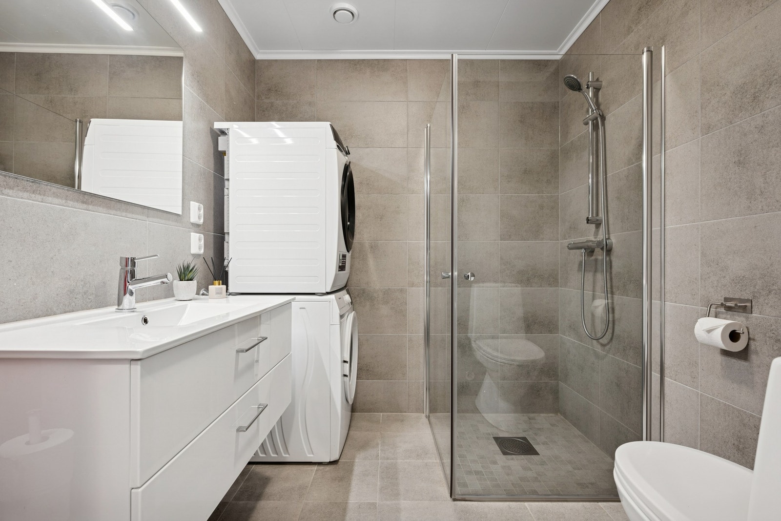 Lekkert baderom med tidløse og moderne farger. Her er det opplegg for både vask- og tørkemaskin. Galleribilde