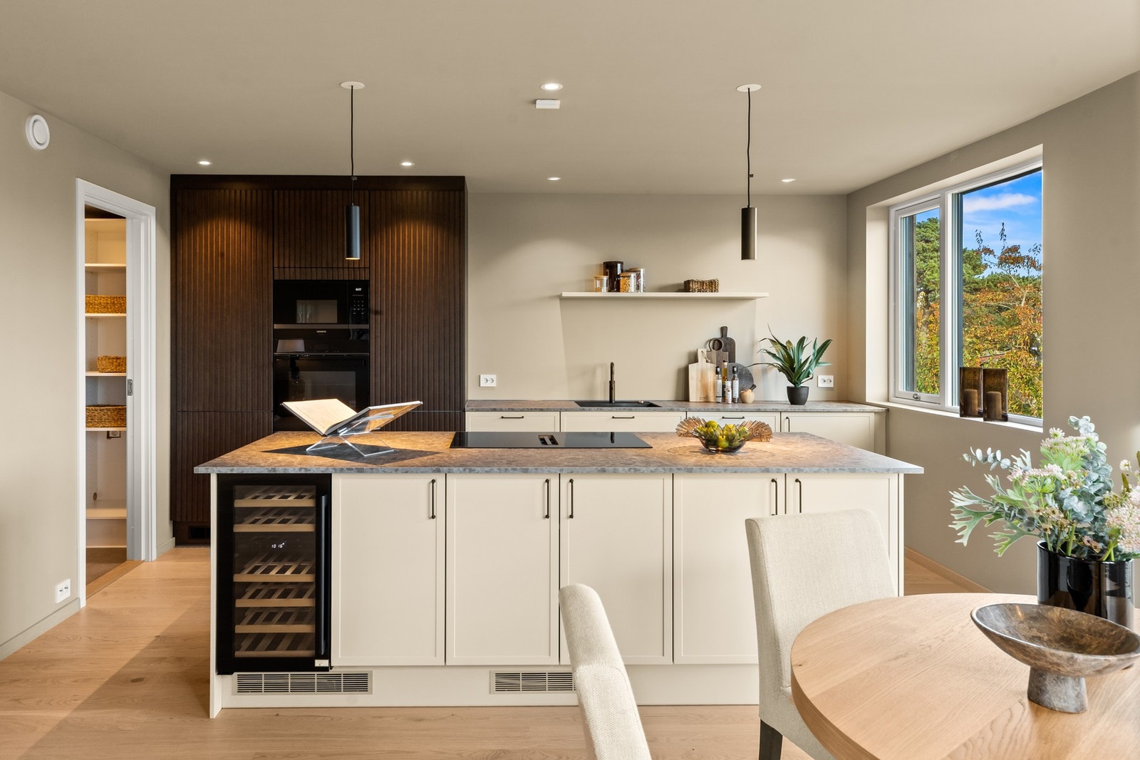 Kjøkkenet er stilrent og moderne med stor kjøkkenøy, vinskap og platetopp med integrert vifte. Galleribilde