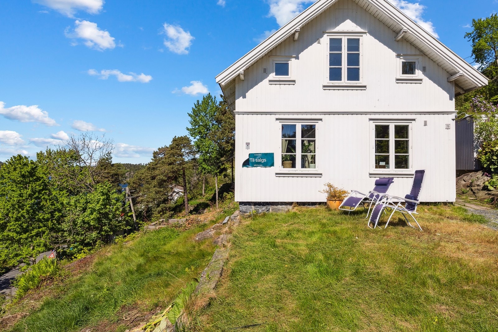 Eiendommen er skrånende mot vest og opparbeidet steinlagt gårdsplass, plenarealer, beplantning og trær. Galleribilde