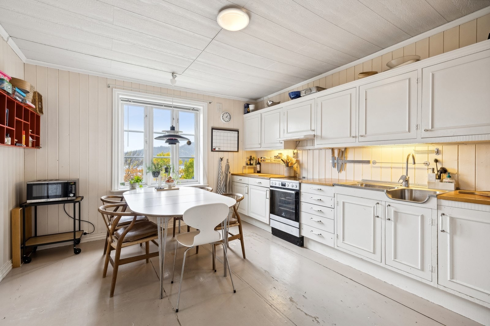 Eldre innredning med lyse, profilerte fronter og plass til frittstående hvitevarer. Galleribilde