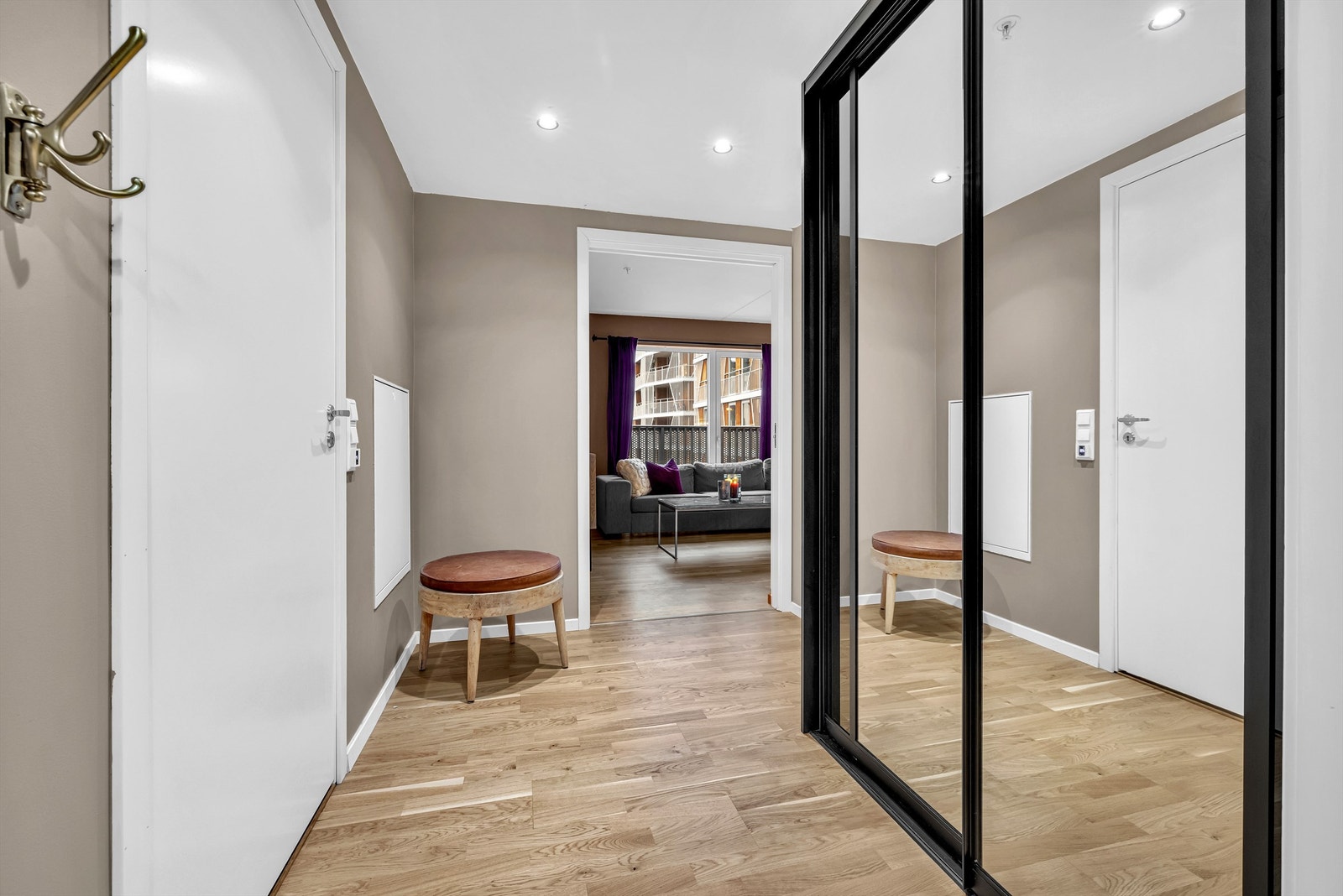 Romslig entrè med skyvedrøsgarderobe, klesopphenging og tilkomst til boligens innvendige bod Galleribilde