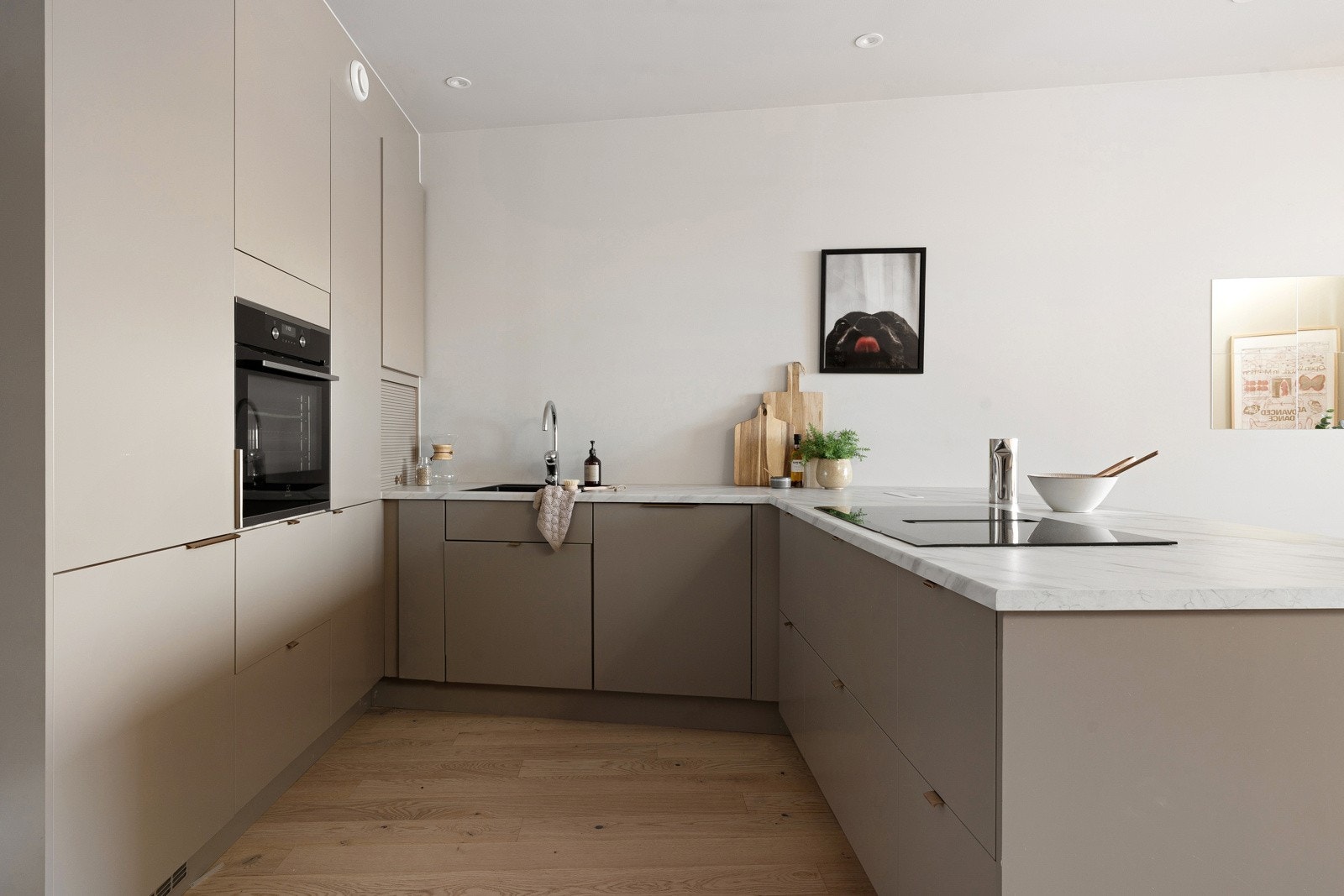 Kjøkkenet er i en stilren beige farge og har rikelig med lagringsplass i både skuffer og skap.