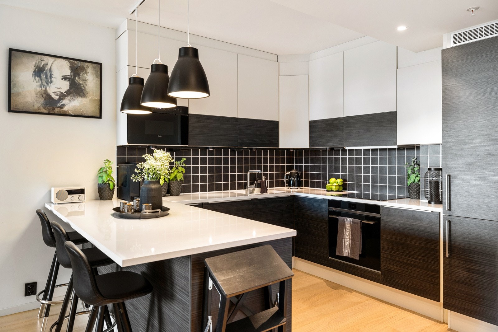 Innredningen har glatte fronter og hvit benkeplate i stein/kompositt. Veggene over benken er kledd med mørke fliser, og under overskapene er det god belysning. Galleribilde