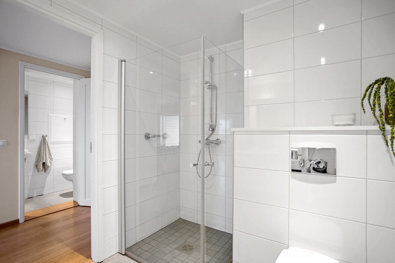 I den romslige dusjen (ca. 1 x 1 meter), er det lagt matchende fliser av mindre dimensjon enn øvrige gulvfliser og dusjvegger med glassdører av herdet glass. Legg også merke til detaljen med nedsenket gulv i dusjsonen og dusjløsningen. Galleribilde