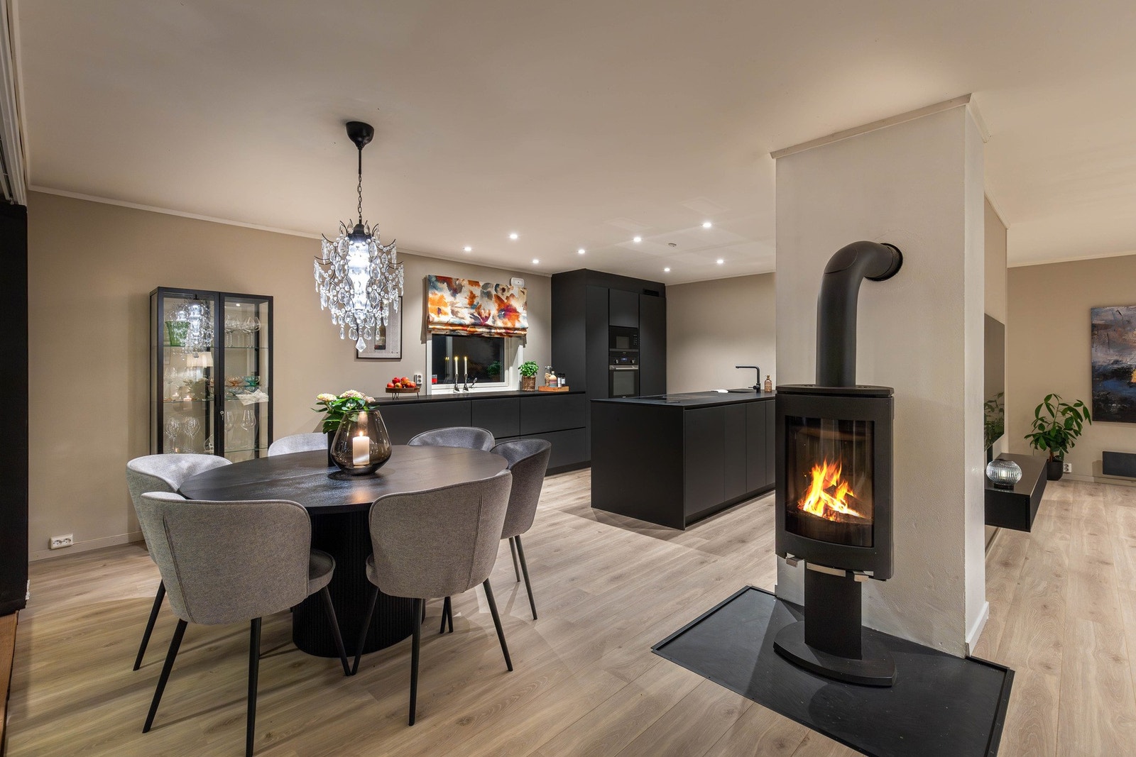 Midt i rommet mellom stue og kjøkken sonene er det installert en koselig peis som gir rikelig med varme og hygge til rommet. Galleribilde