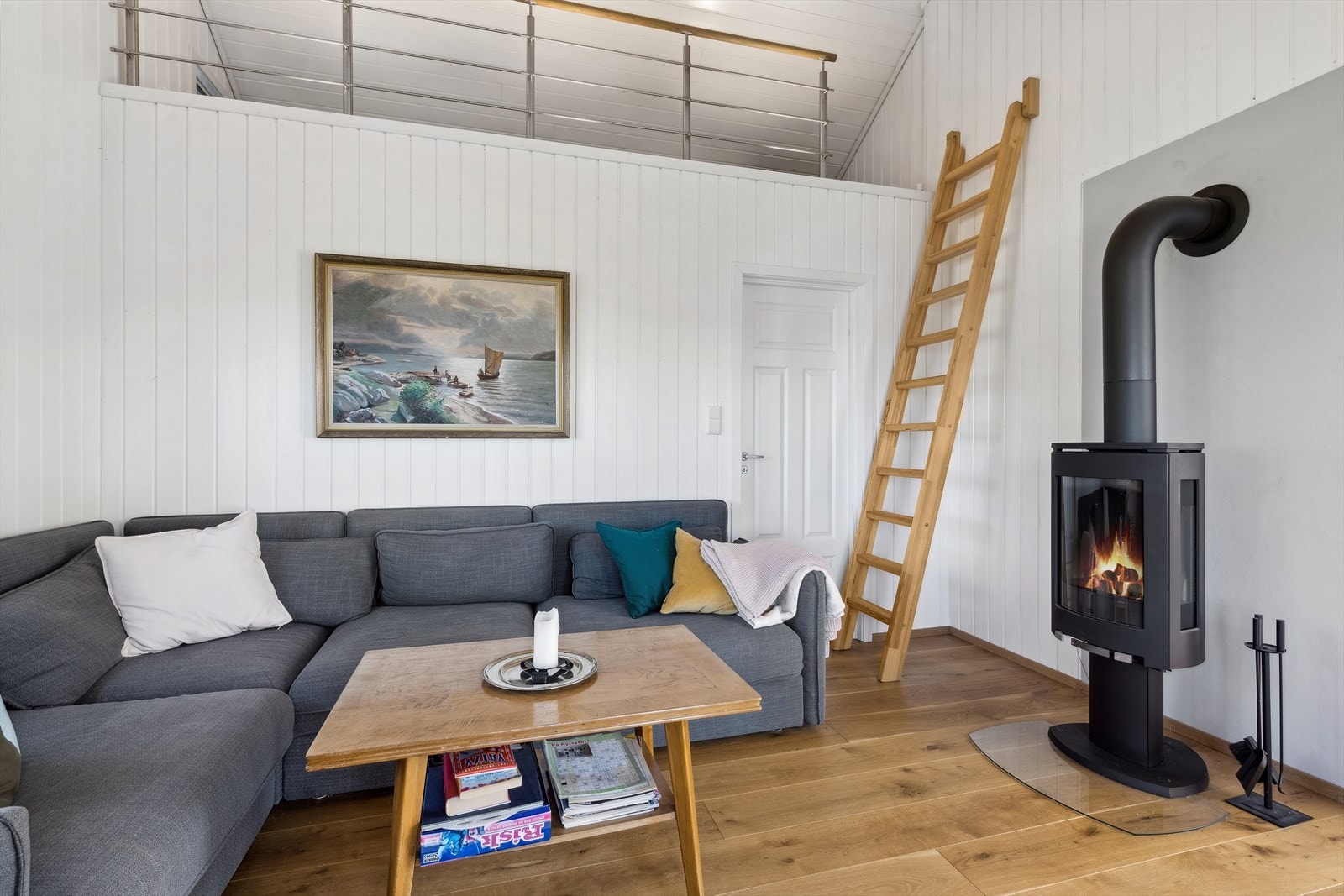 Romslig stue med plass til en stor sofa foran vedovnen. Galleribilde