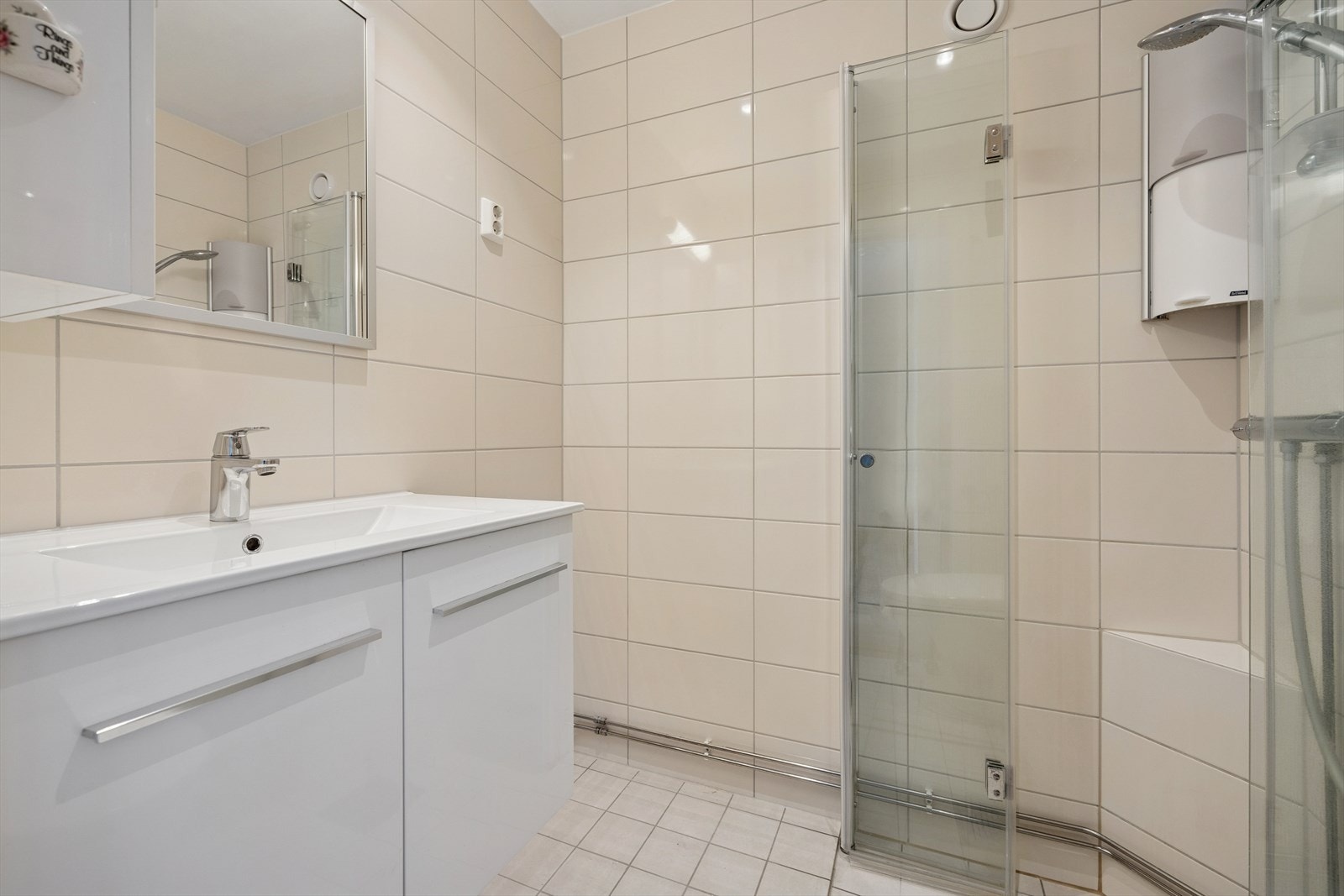 Badet har varmekabler i gulvet, dusjdører i glass og opplegg for vaskemaskin. Galleribilde