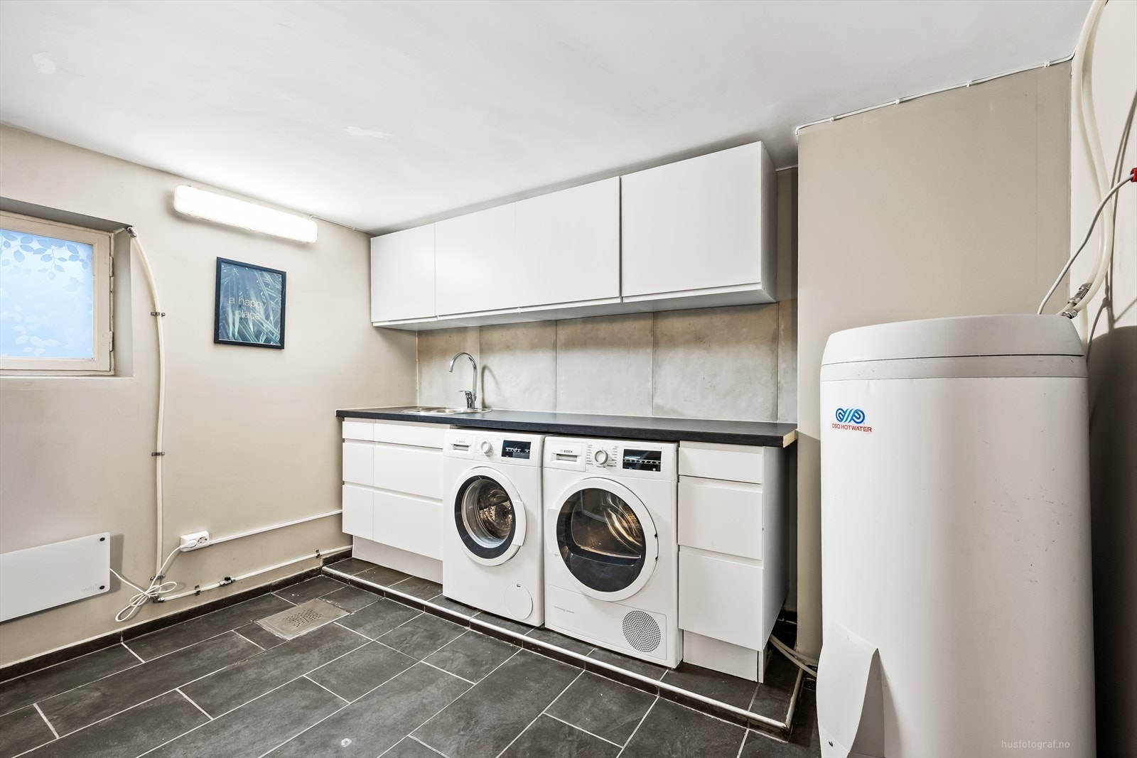 Praktisk innredet vaskerom i underetasjen med romslig innredning med over- og underskap. Galleribilde