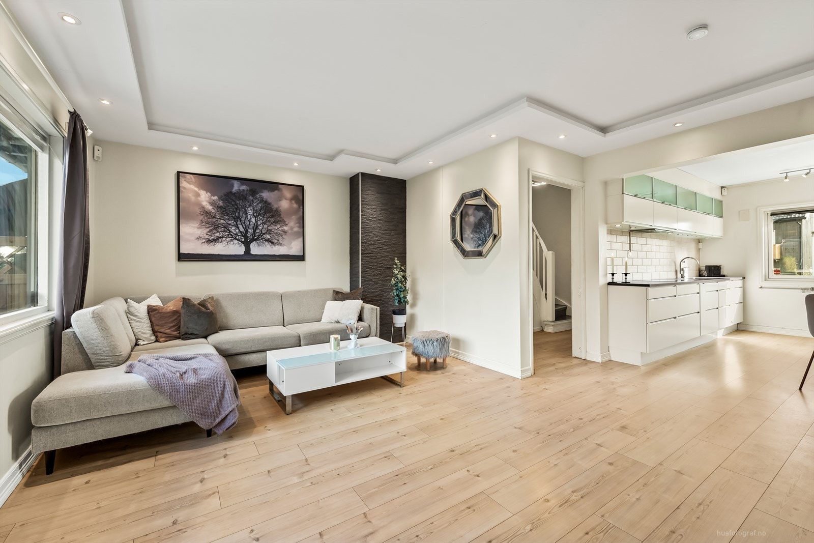 Den lyse og innbydende stuen har pene overflater med laminat på gulv, slette lysmalte vegger og utstrakt bruk av downlights i himling, som gir et moderne uttrykk. Galleribilde