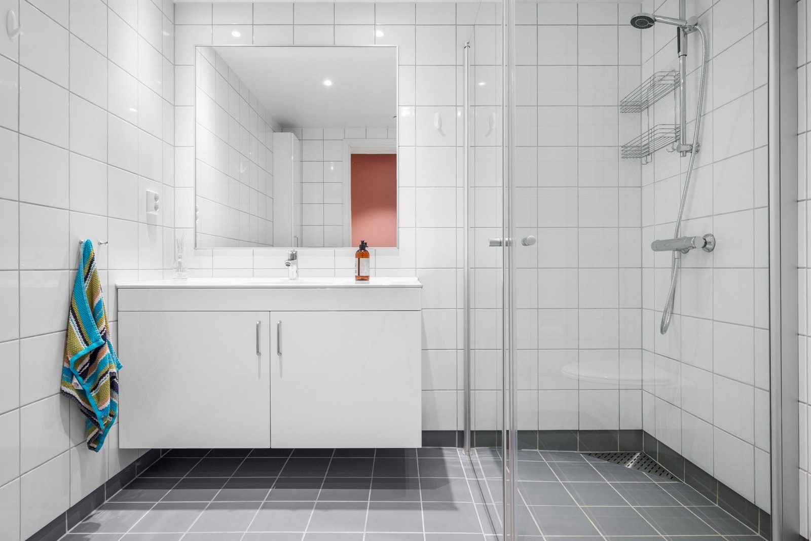 Badet er helfliset, utstyrt med downlights, dusjhjørne og vegghengt toalett. Galleribilde