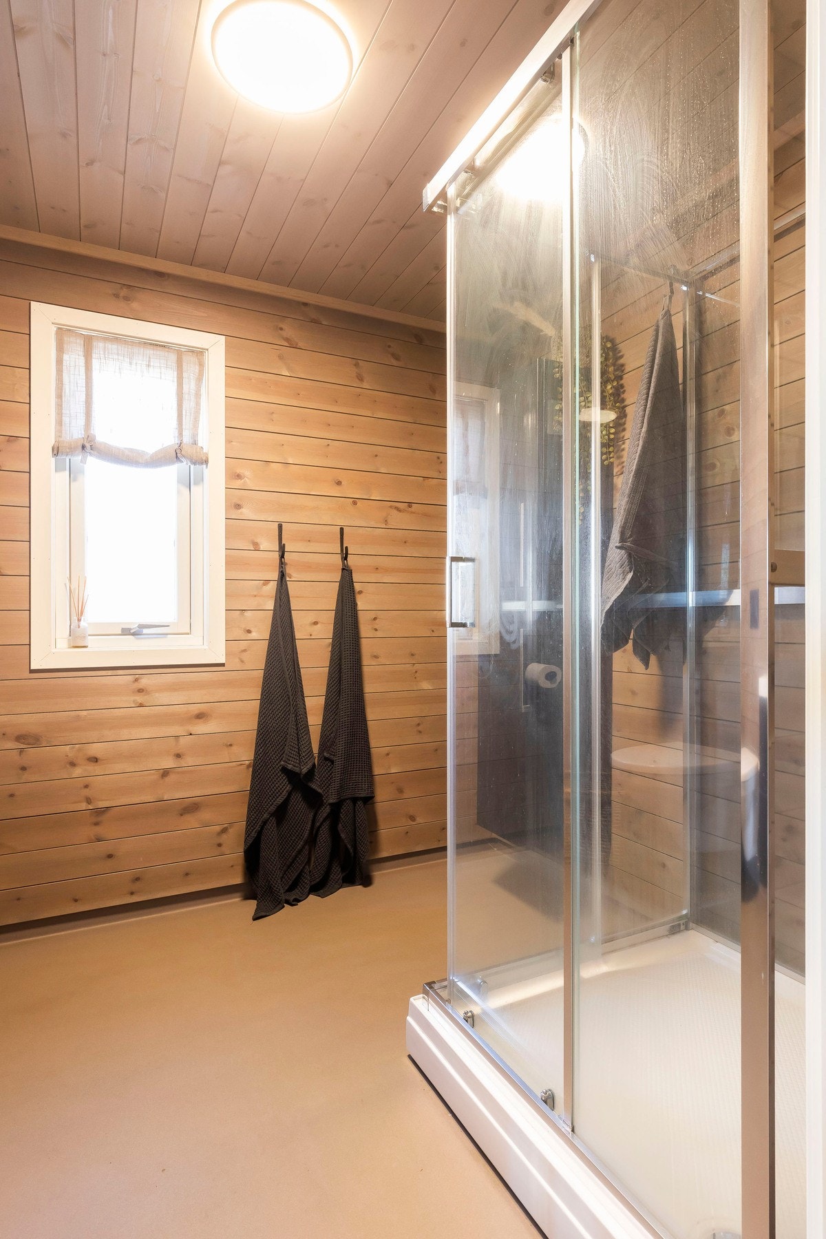 Rommet inneholder et vegghengt toalett, dusjkabinett og en vask med baderomsinnredning som gir noe oppbevaringsplass. Galleribilde