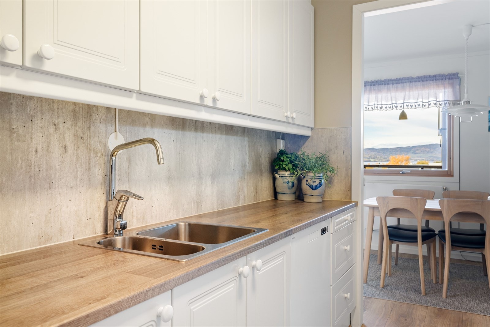 Laminerte benkeplater med nedfelt oppvaskkum i rustfritt stål. I benkeryggen er det plate for enkel rengjøring. Galleribilde