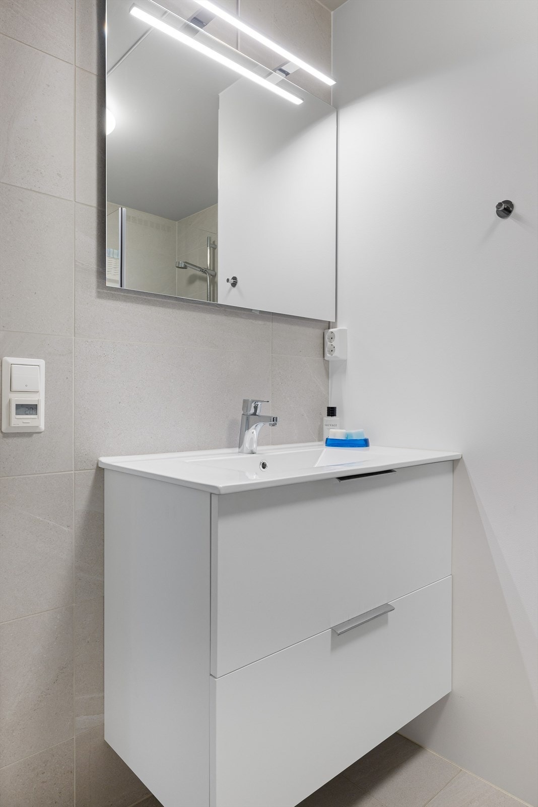 Baderomsinnredning med skuffer og heldekkende servant med ett-greps blandebatteri. I overkant av servanten er det speil og lyslist. Elektrisk uttak på vegg. Galleribilde