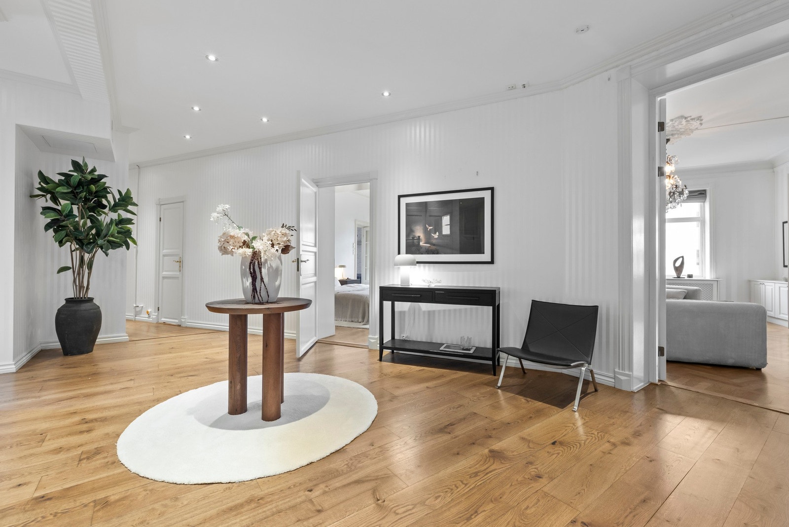 Vel inne har leiligheten en stor hall med dimbare downlights, stripete tapet og 1-stavs parkettgulv. Imponerende takhøyde er gjennomgående, noe som bidrar til en upåklagelig atmosfære i leiligheten.