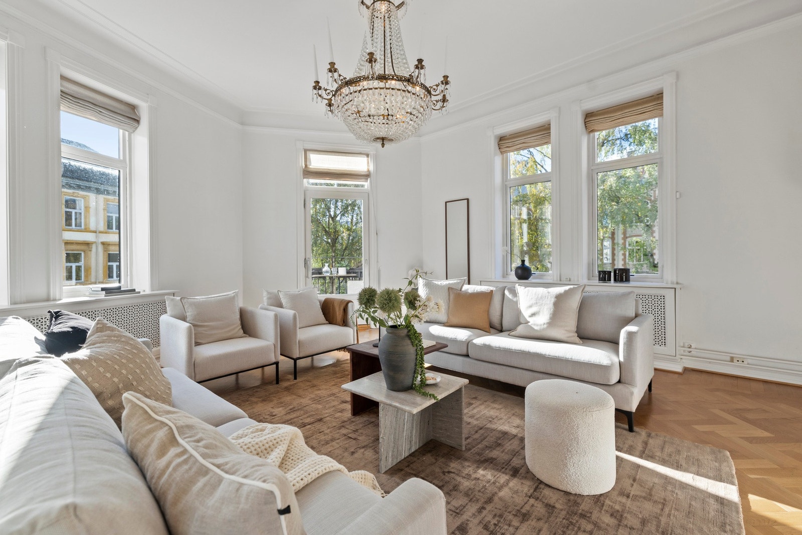 Begge stuene er smakfullt innredet med fiskebensparkett, nydelige takrosetter og hvite vegger for et delikat uttrykk.