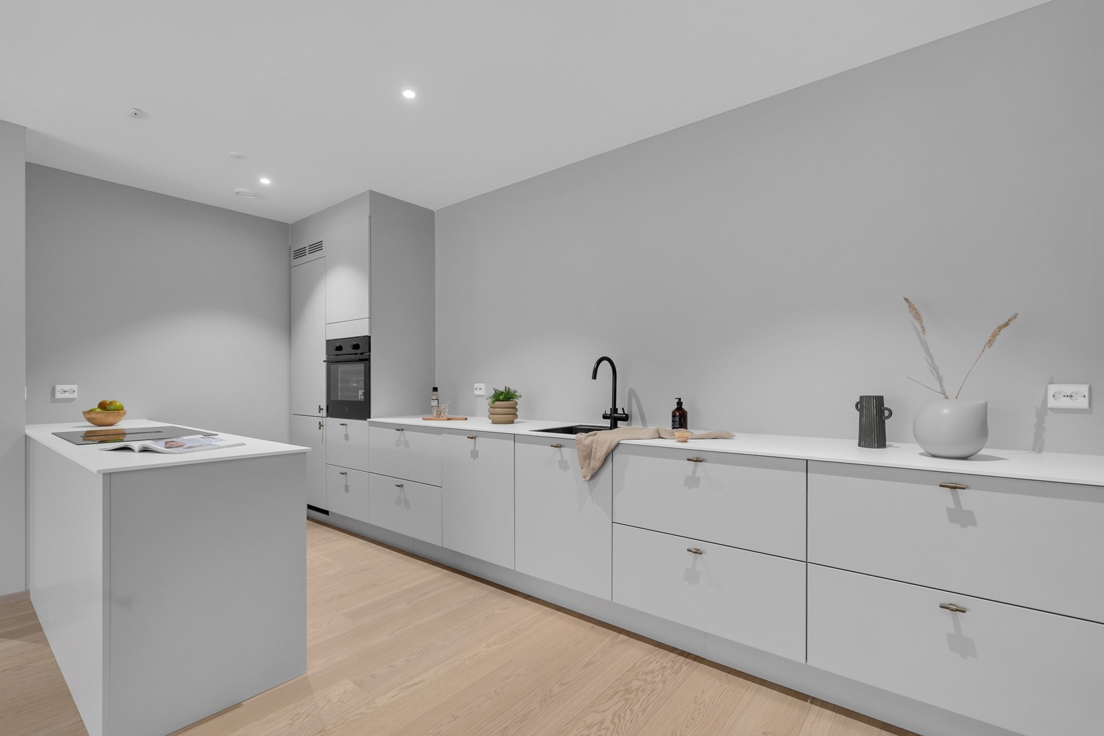 Lekkert kjøkken med øy sørger for et behagelig arbeidsrom. Over kjøkkenbenken er det lagt klart til to uttak for vegglamper. Galleribilde