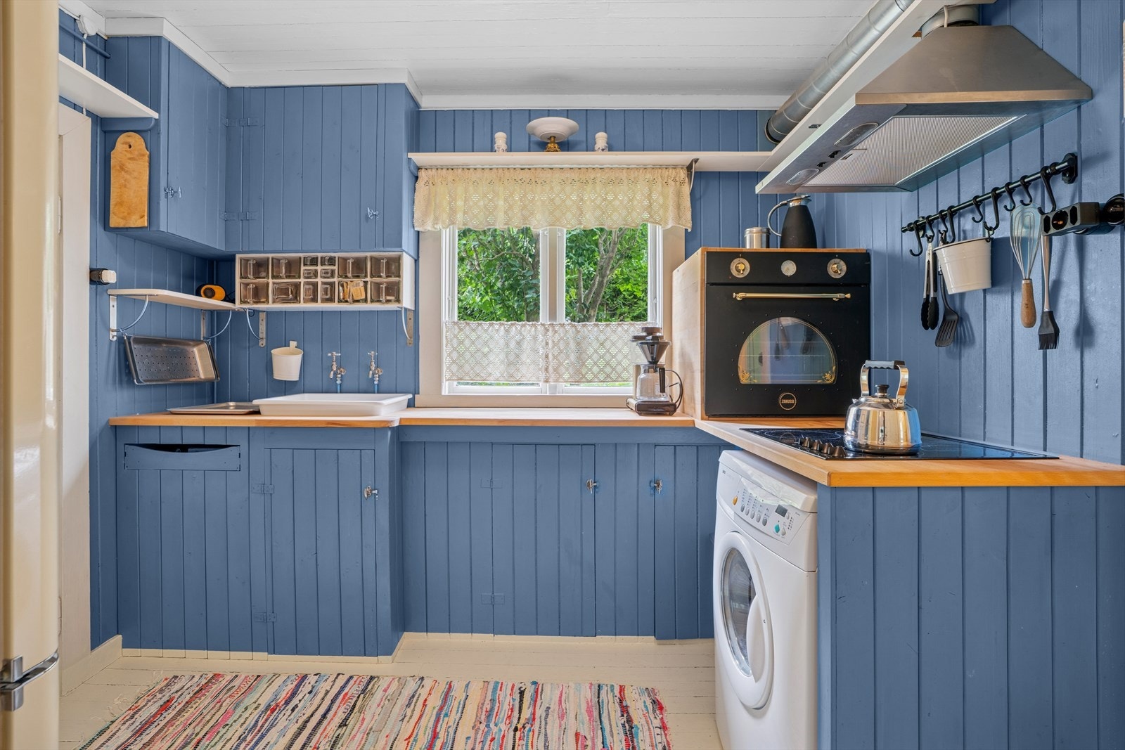 Sjarmerende kjøkken i fin blåfarge. Plassbygd kjøkkeninnredning med malt panel på fronter og heltre benkeplate. Galleribilde