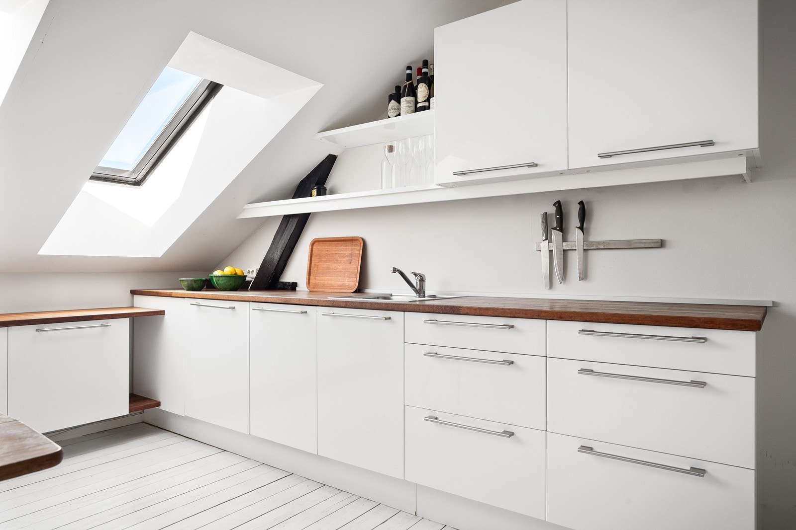 Kjøkkenet er innredet med hvite slette fronter og benkeplatr av tre Galleribilde