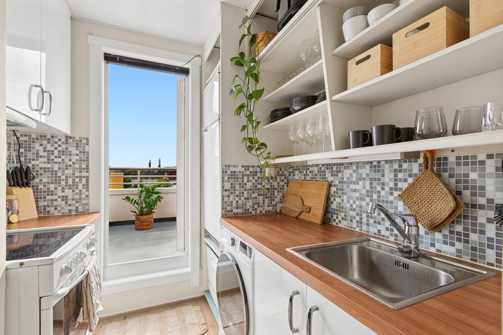 Pen kjøkkeninnredning med folierte skrog med slette fronter og laminert benkeplate. Utgang til solrik takterrasse. Galleribilde