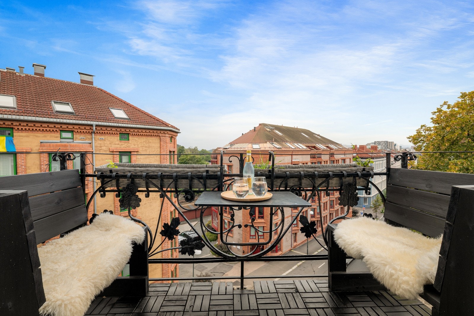 Koselig balkong med trefliser på gulv og klassisk rekkverk av sort metall. Galleribilde