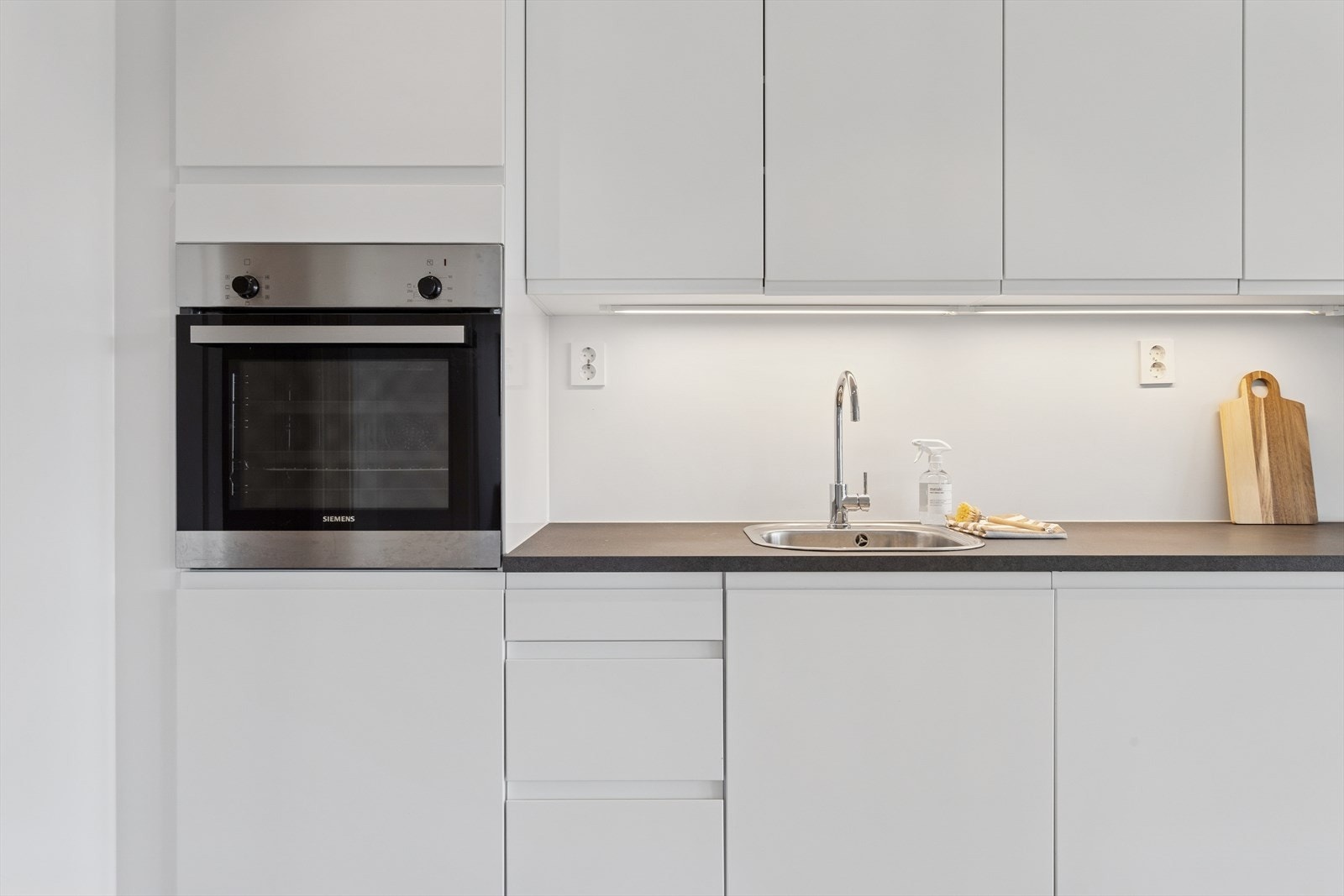 Underskap består av både tradisjonelle slagdørsskap samt praktiske kolonialskuffer som gir ekstra god oversikt. Både dører og skuffer har dempere for sømløs lukking. Legg også merke til at overskapene er ført helt opp til himlingen. Galleribilde