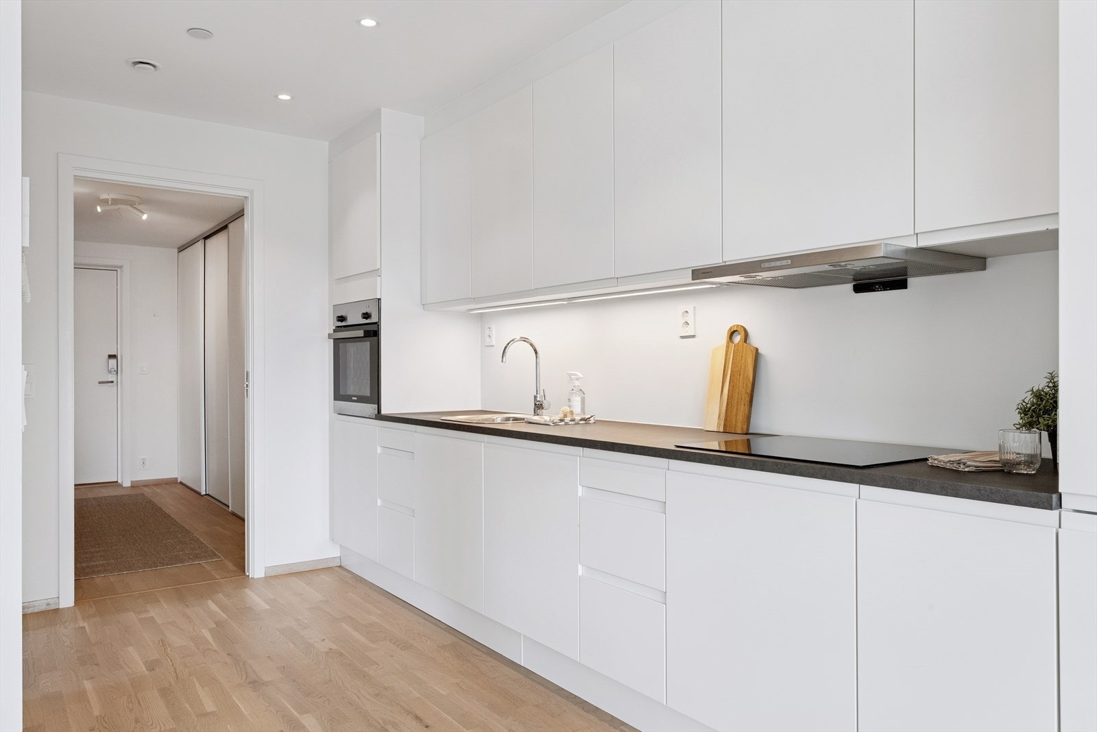 Hjemmets kjøkken har en strategisk plassering, ytterst i den åpne sonen for stue-/kjøkken. Leiligheten er innredet med et moderne, men likevel klassisk og stilrent kjøkken fra danske HTH-kjøkken. Galleribilde