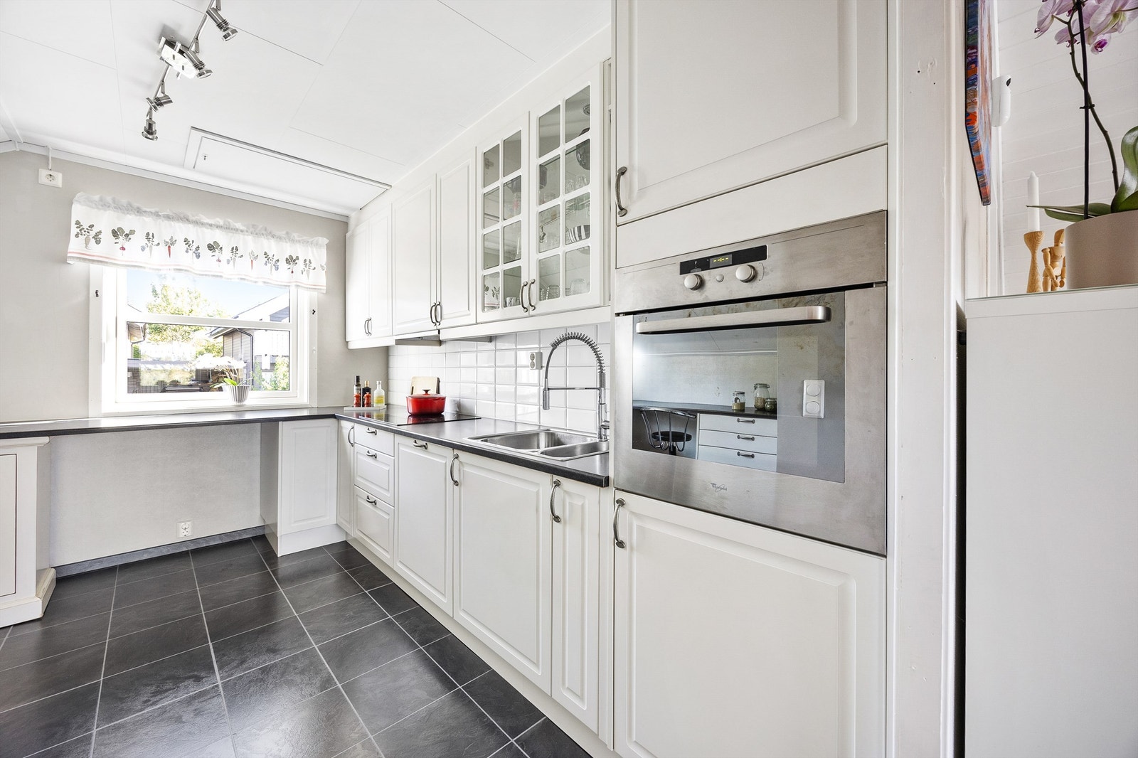 Kjøkkeninnredning fra Norema fra 2009 bestående av profilerte fronter, over- og underskap med fliser mellom skapet og belysning under overskapet. Integrerte hvitevarer medfølger boligen. Galleribilde