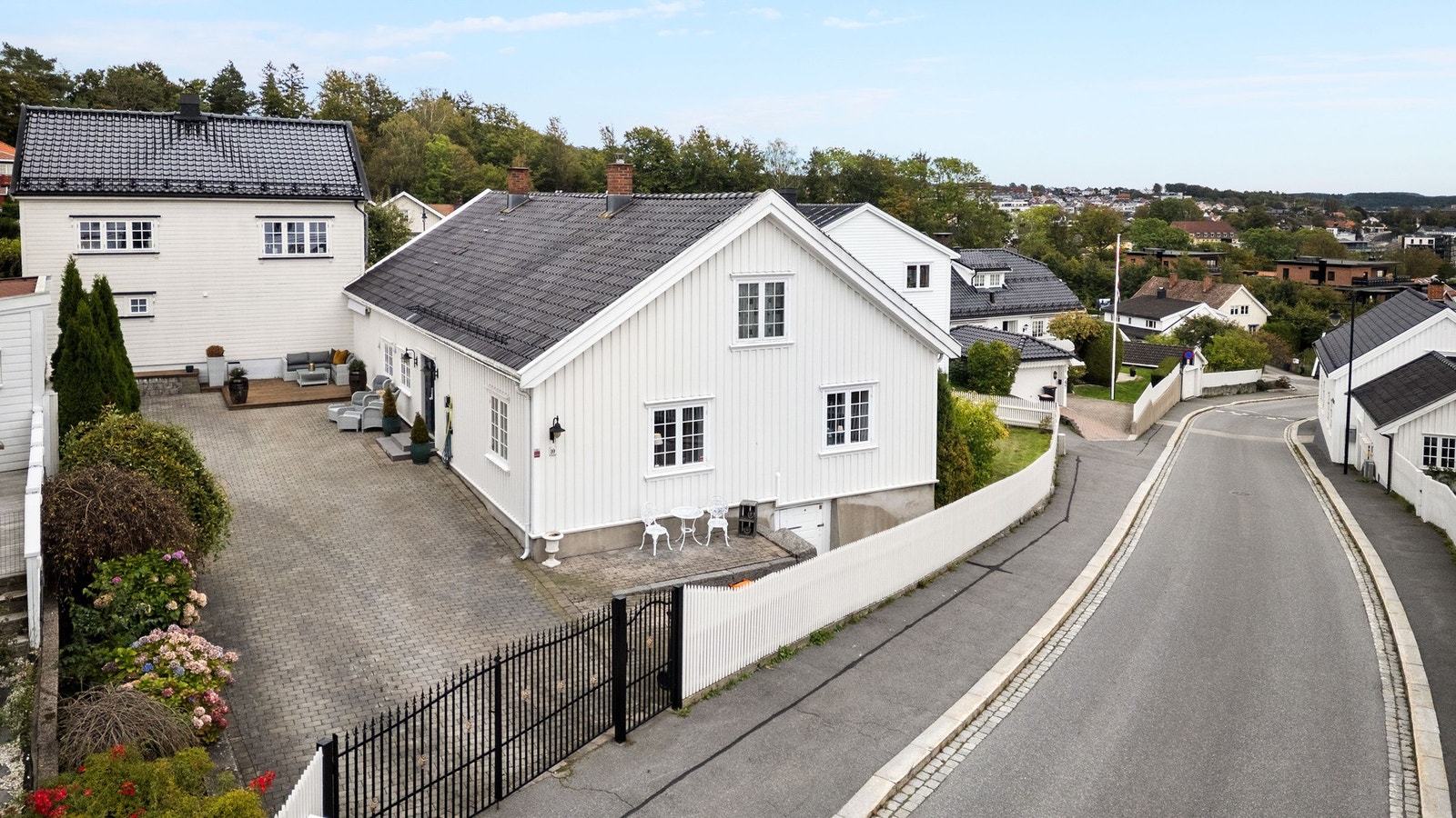 Hagen er inngjerdet med hvitt stakittgjerde og port mot veien. Galleribilde