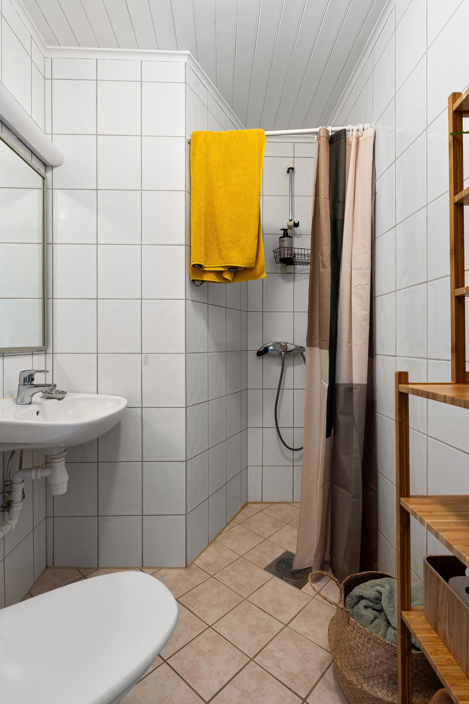 Flislagt bad. Det er en vaskekjeller i huset hvor det står en vaskemaskin som tilhører hybelen.