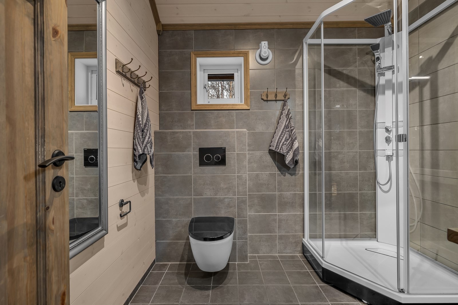 Flott badrom med vegghengt toalett og dusjkabinett. Galleribilde