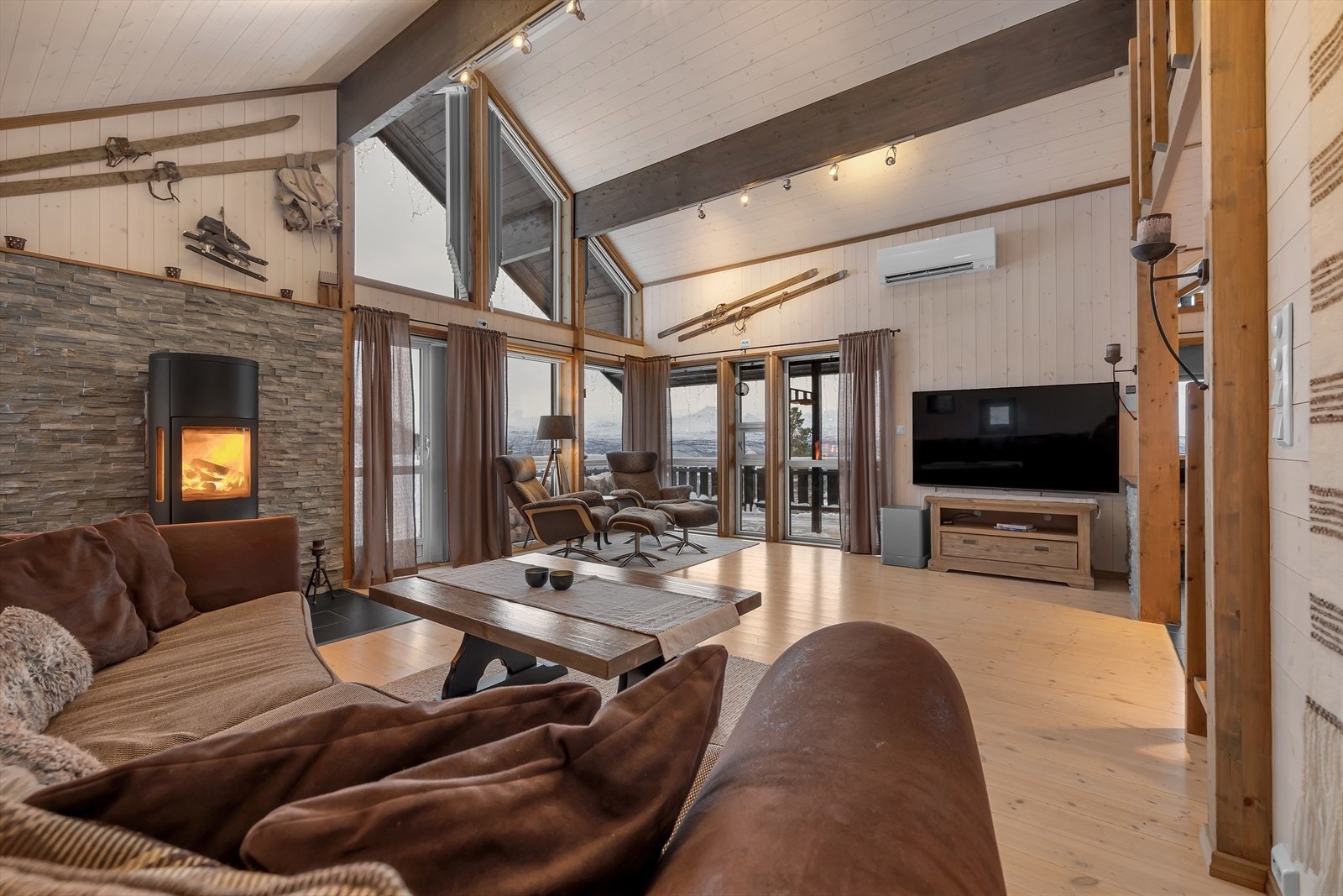 Romslig stue med store vindusflater, blant annet med vindu fra gulv til tak mot sørøst. Galleribilde