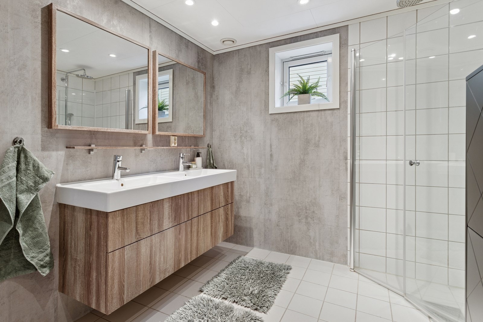 Baderommet er utstyrt med innredning med servant, gulvmontert toalett, og dusjvegger av glass. Galleribilde