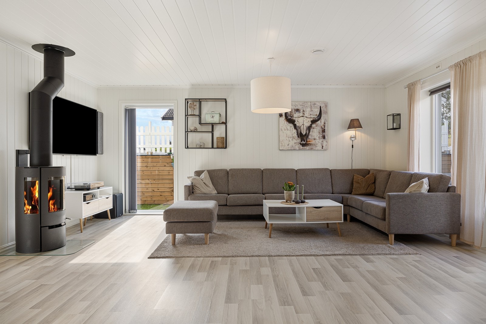 Atmosfæren i stuen er lun og god, med både peisovn og gulvvarme montert. Galleribilde