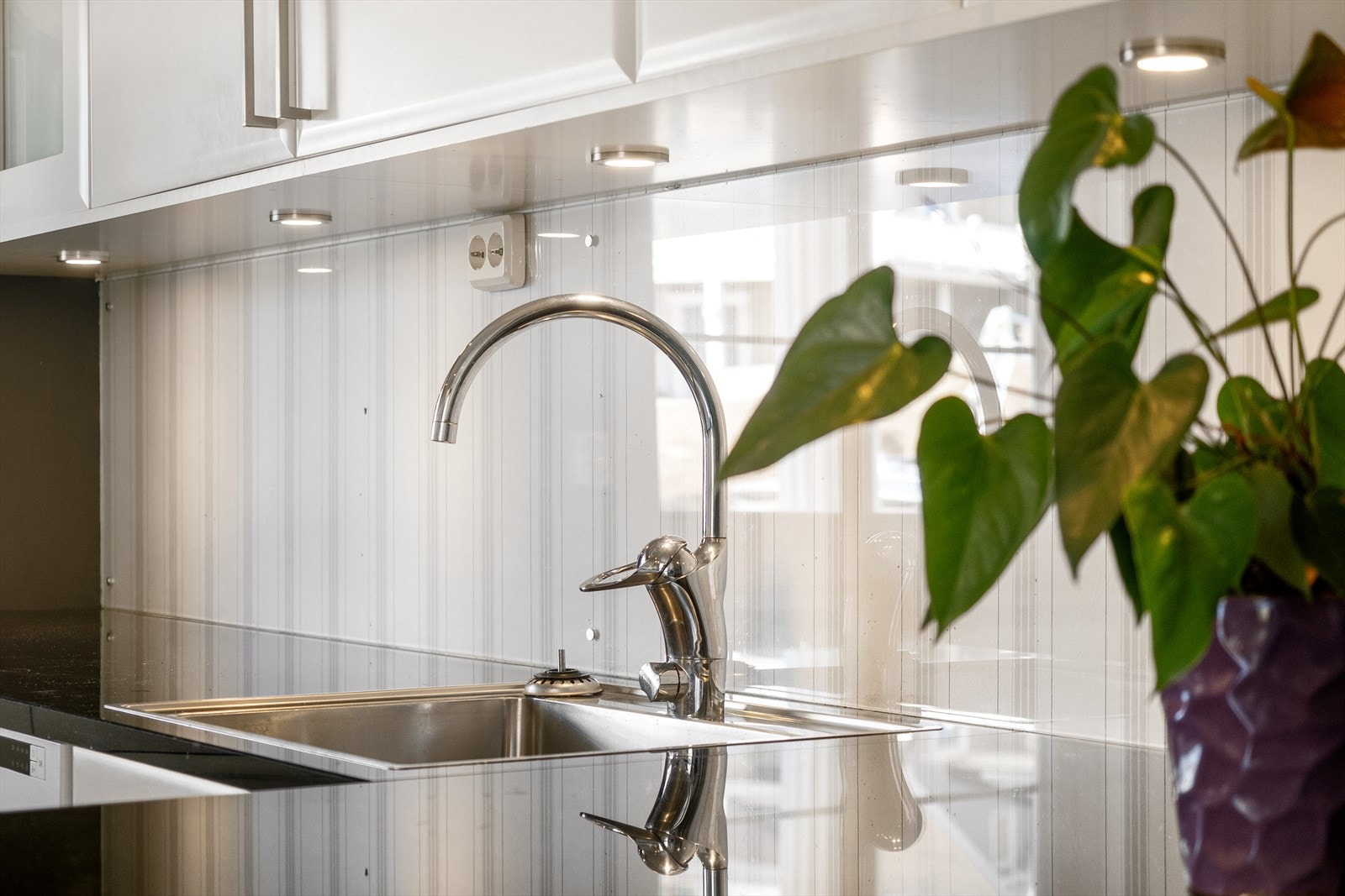 Beskyttelsesplate i glass mellom benkeplate og overskap. Galleribilde