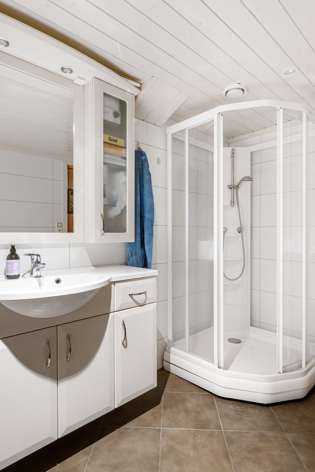 Badet er innredet med servantskap med servant, opplegg for vaskemaskin og dusjkabinett. Galleribilde