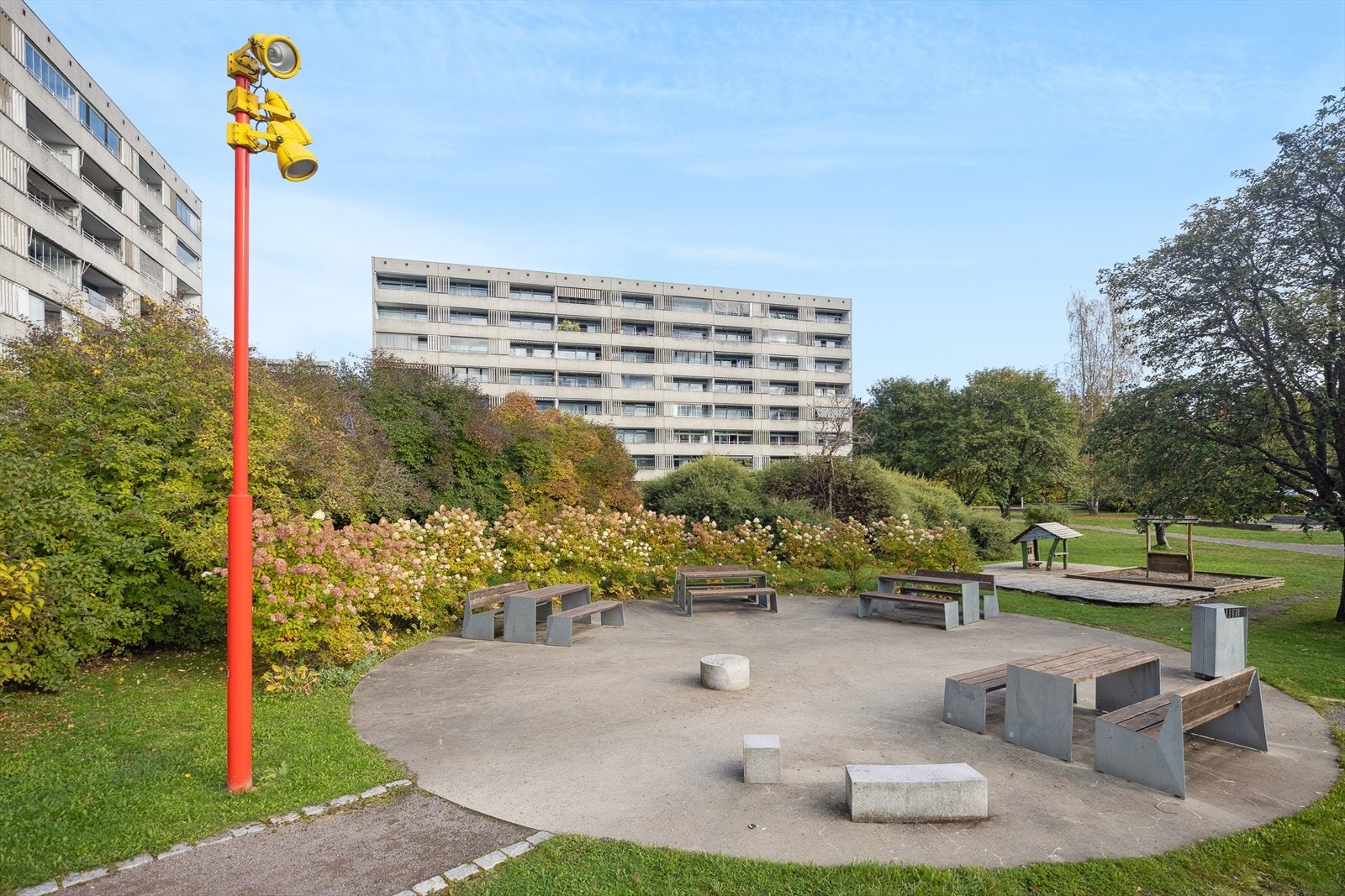 Pent opparbeidet uteområde med sittegrupper og beplantning - et sosialt og barnevennlig område som inviterer til hyggelige samlinger utendørs. Galleribilde