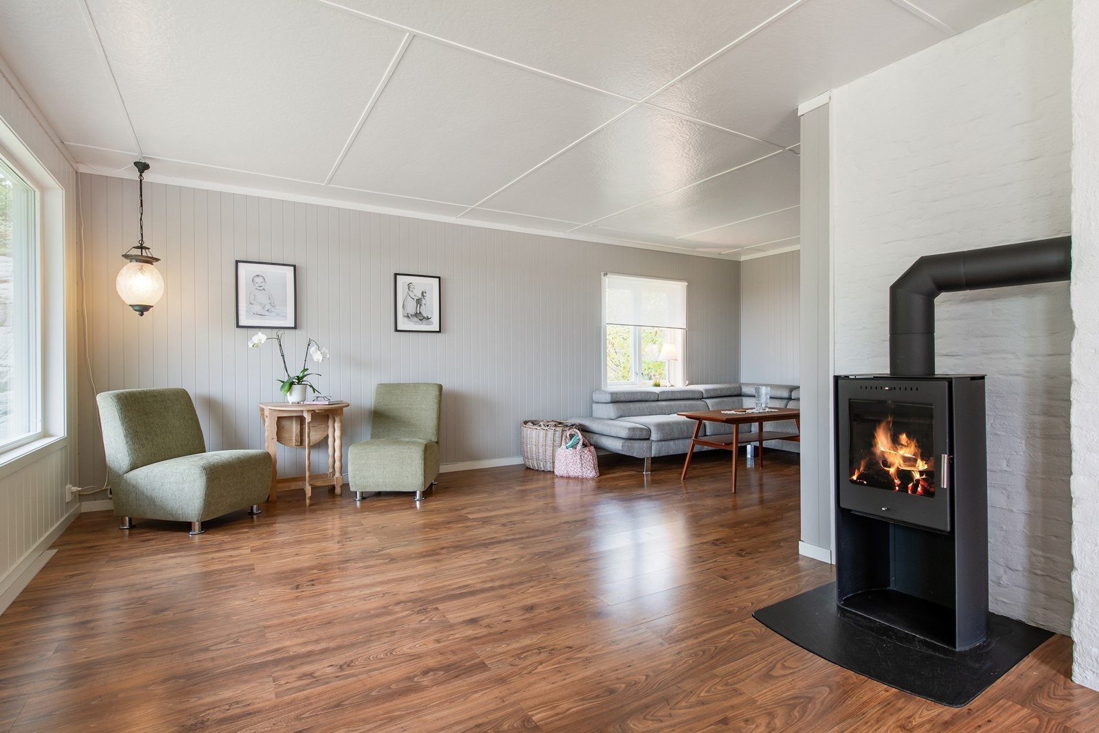 Stue og oppholdsrom med utsikt over jordet på fremsiden av huset Galleribilde