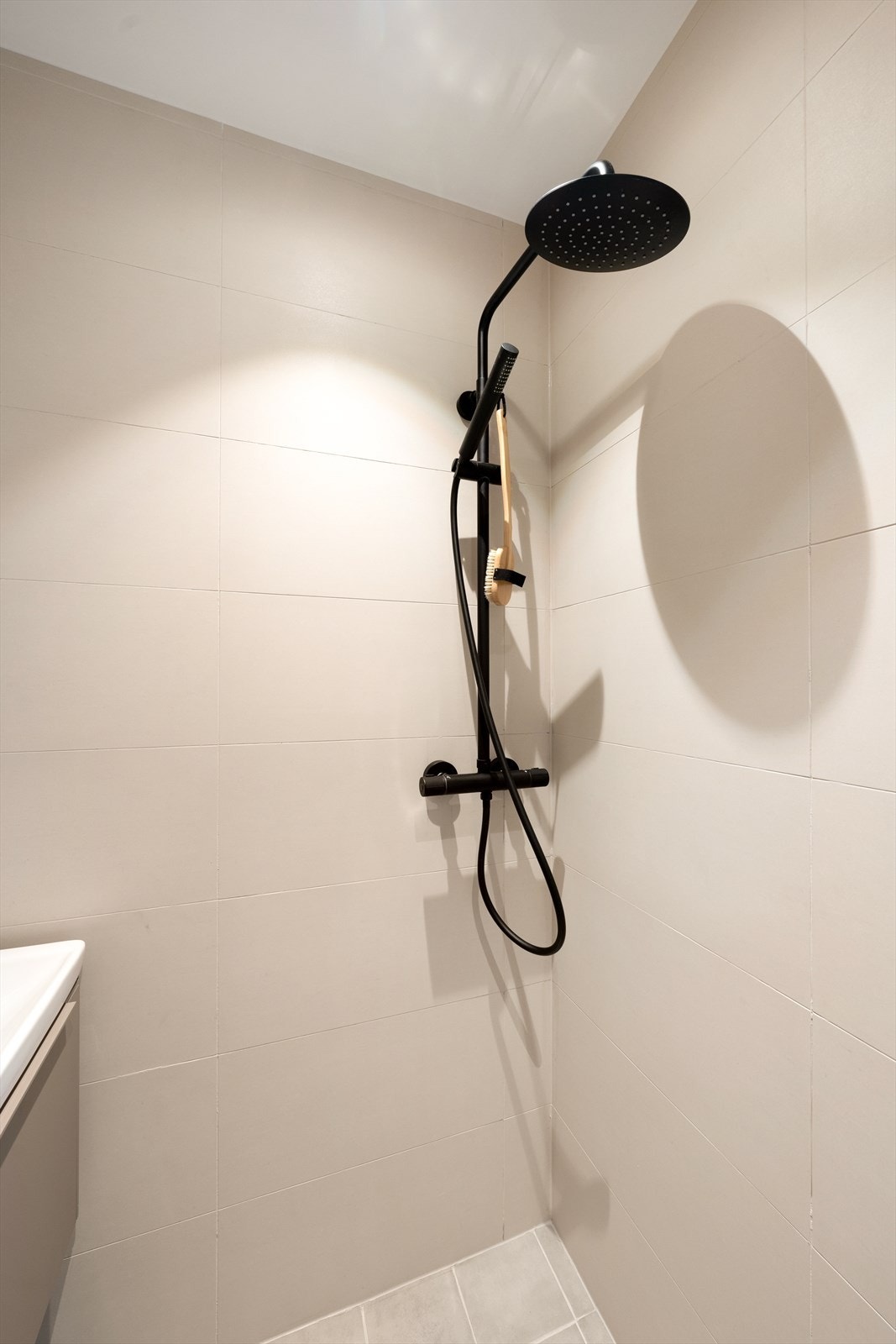 Regnfallsdusj og armatur i sort. Gulvvarme og downlights i tak. Galleribilde